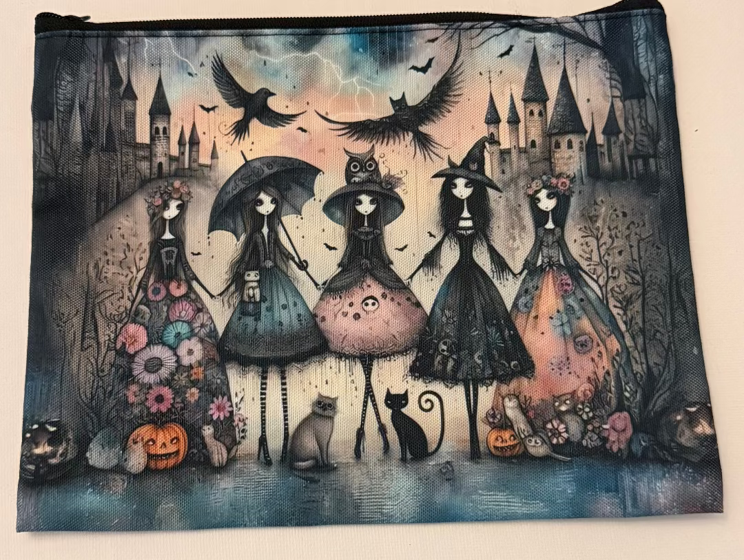A rectangular zippered pouch featuring a detailed Halloween illustration of four witch-like figures in dresses, crows, bats, pumpkins, and a haunted castle under a stormy sky.