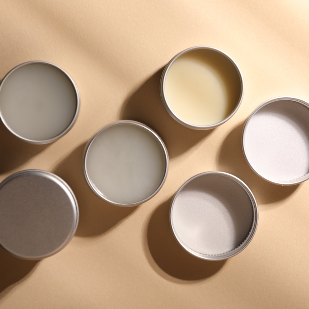 Six round metal tins on a beige background