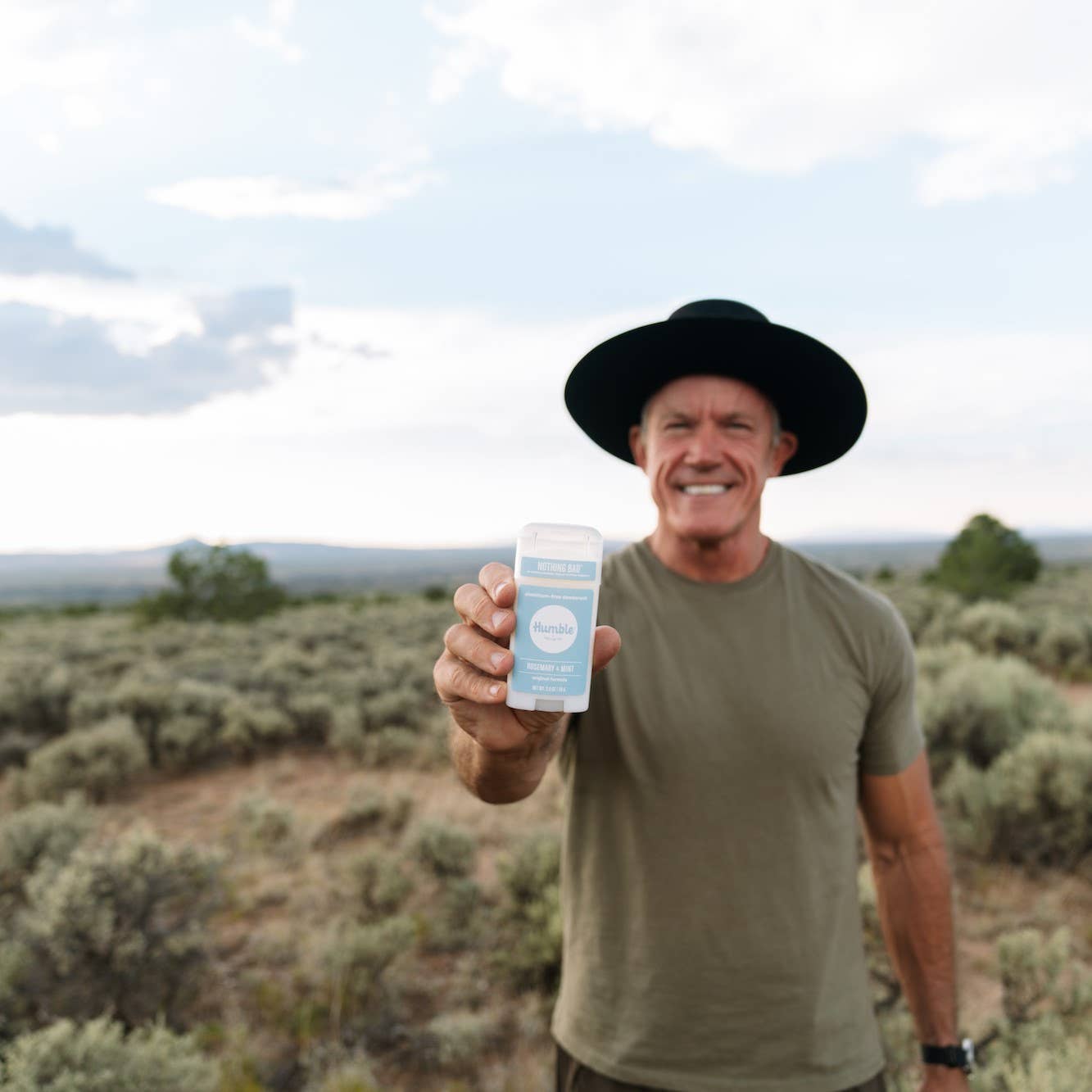 Man outdoors holding Humble original formula deodorant – Rosemary & Mint scent, aluminum free -available at www.aromathyme.com