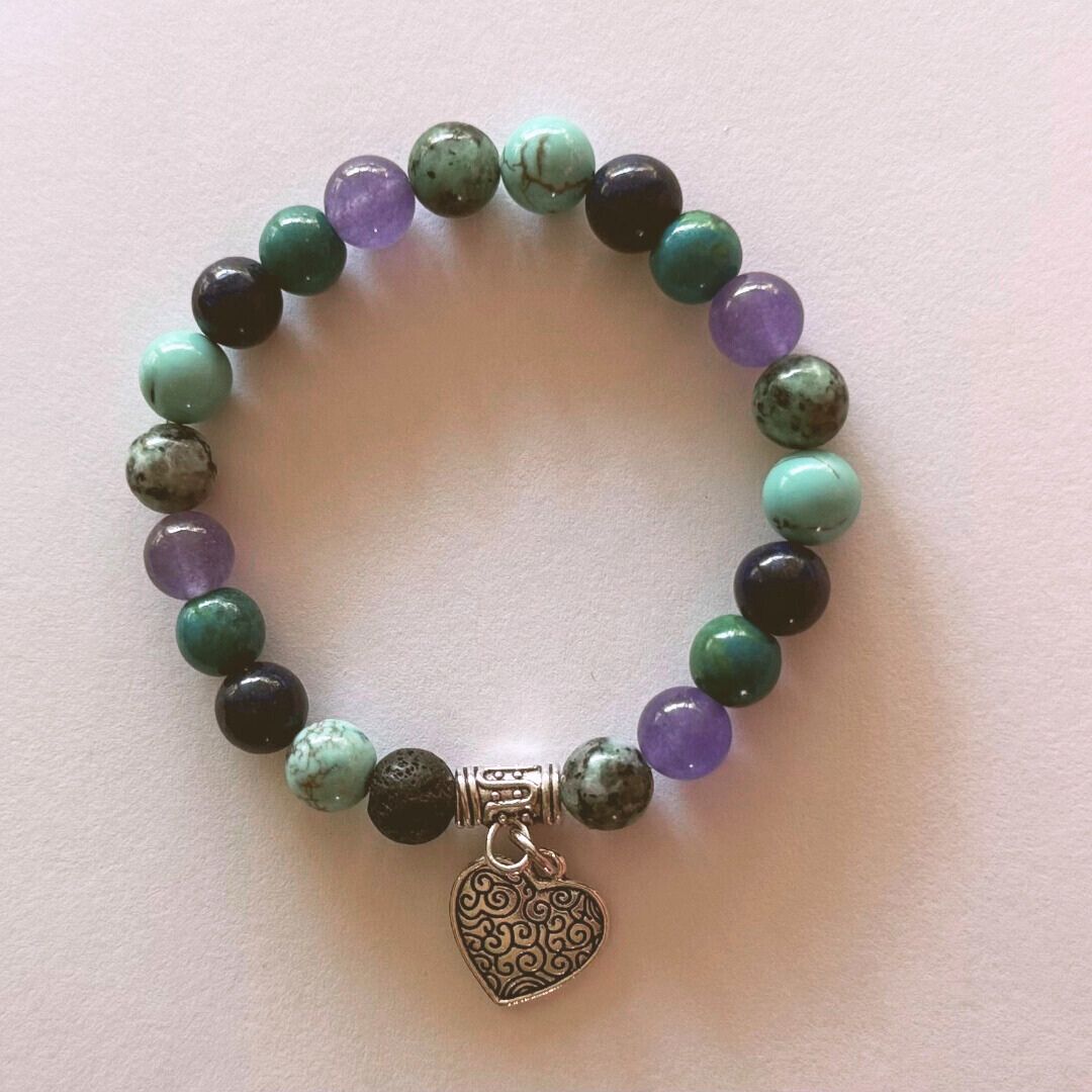 gemstone bracelet with a heart charm on a light pink background