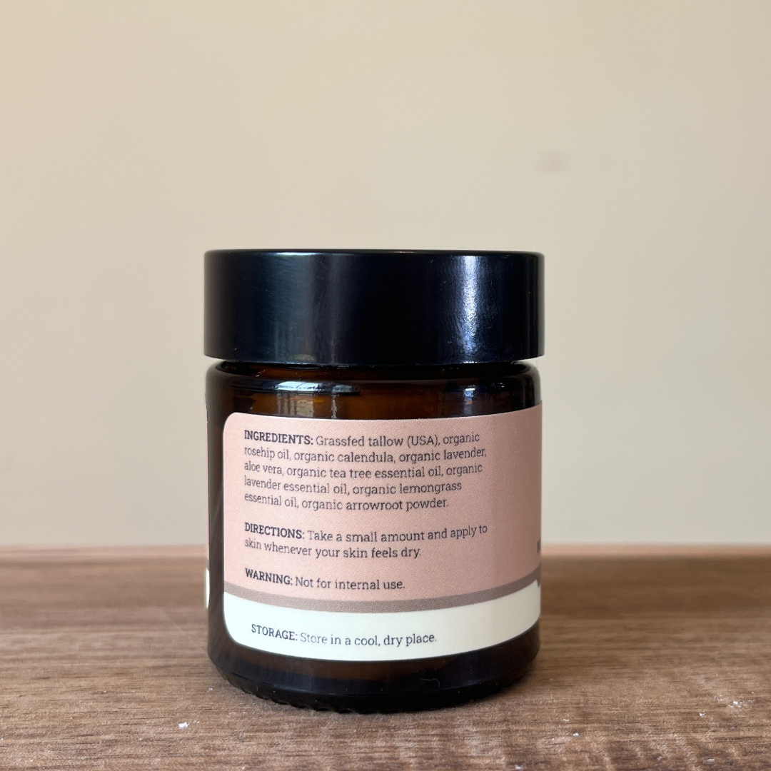 Grass Fed Tallow Jar with a label ingredients and directions on a wooden surface and beige background